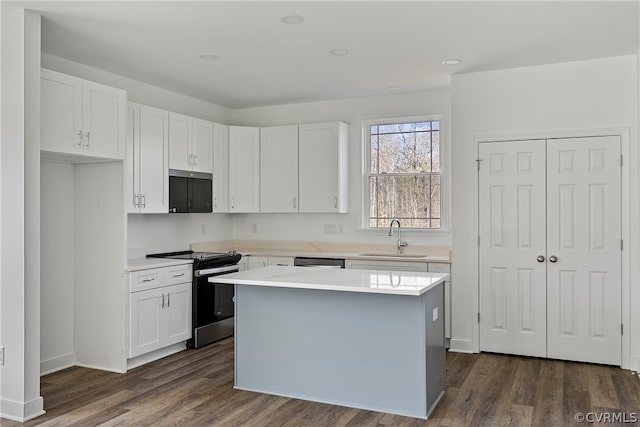 kitchen featuring a center island, white cabinetry, appliances with stainless steel finishes, dark hardwood / wood-style floors, and sink