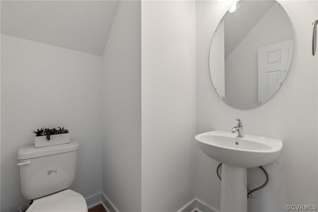 bathroom with baseboards, toilet, and lofted ceiling