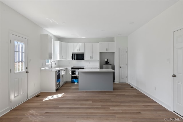 kitchen featuring a center island, white cabinetry, stove, and hardwood / wood-style floors