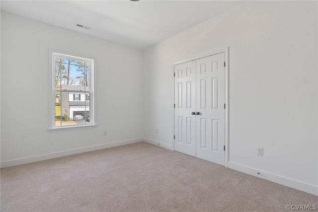 unfurnished bedroom with visible vents, baseboards, light colored carpet, and a closet