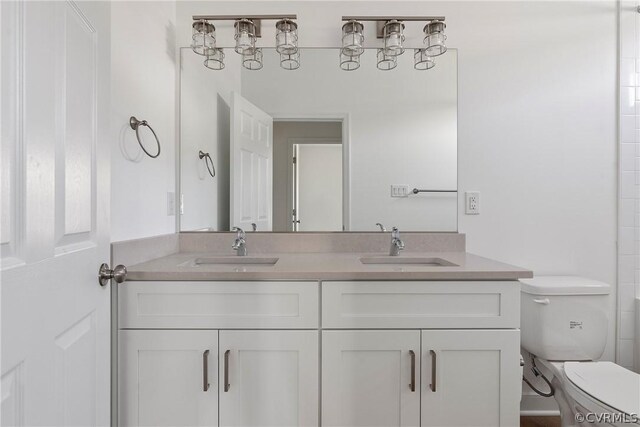 bathroom featuring double sink, toilet, and vanity with extensive cabinet space