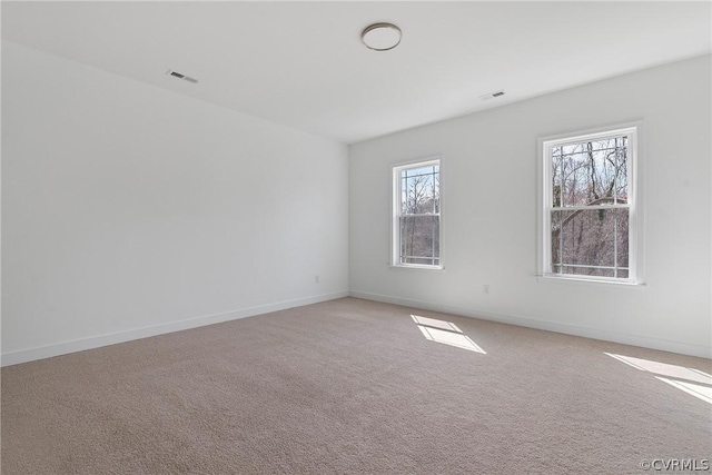 spare room with visible vents, baseboards, and light colored carpet