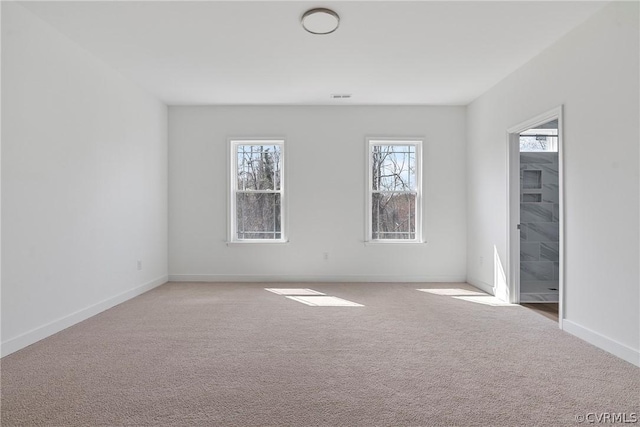 carpeted empty room with visible vents, plenty of natural light, and baseboards