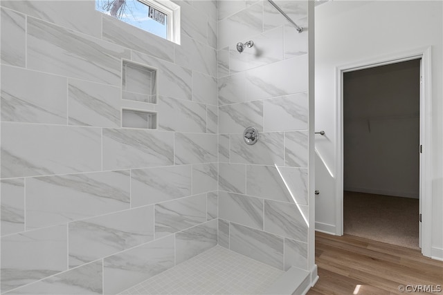 bathroom with a tile shower and hardwood / wood-style floors