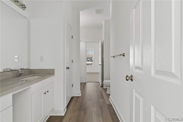 bathroom with large vanity, toilet, and hardwood / wood-style floors