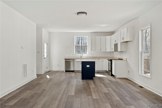 kitchen with plenty of natural light, stainless steel appliances, light wood-type flooring, and white cabinetry