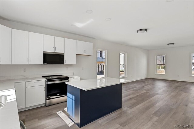 kitchen featuring white cabinets, appliances with stainless steel finishes, a center island, and light wood-type flooring