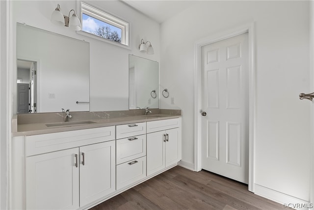 bathroom with double sink, large vanity, and wood-type flooring