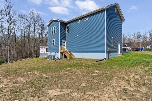 rear view of house featuring a yard and central AC unit