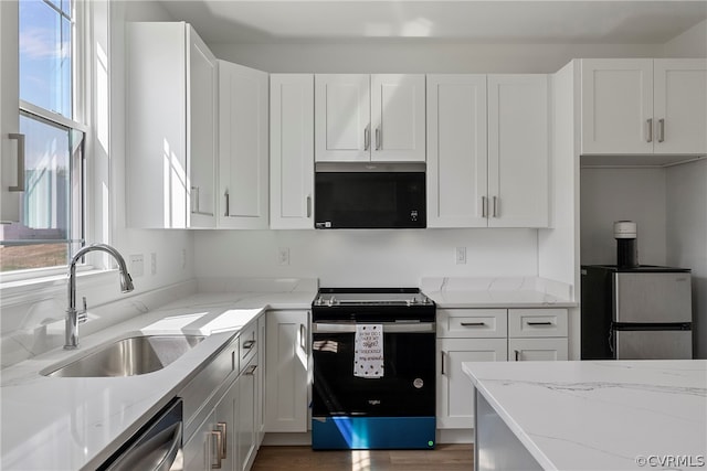 kitchen featuring white cabinetry, appliances with stainless steel finishes, wood-type flooring, sink, and light stone counters