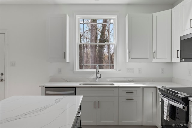 kitchen with plenty of natural light, appliances with stainless steel finishes, sink, and light stone counters