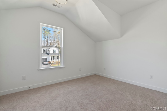 additional living space featuring light colored carpet and vaulted ceiling