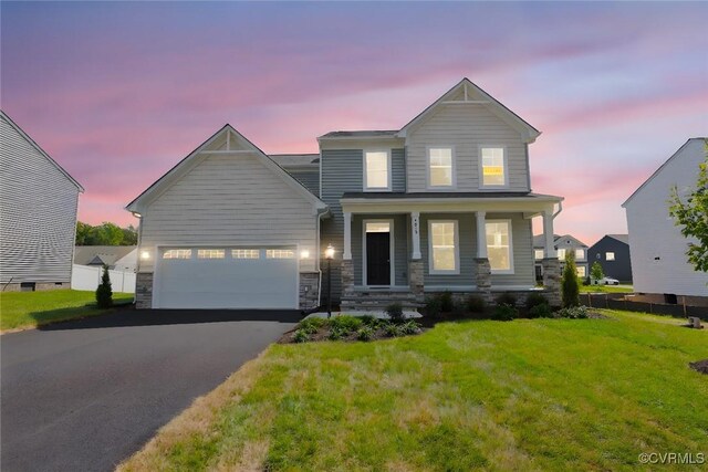 view of front of house with a lawn, a porch, and a garage