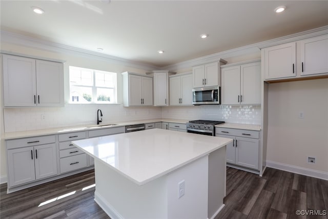 kitchen featuring appliances with stainless steel finishes, a center island, dark wood-type flooring, and tasteful backsplash