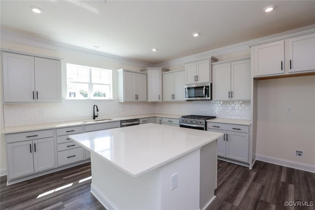 kitchen with crown molding, appliances with stainless steel finishes, dark wood finished floors, and a sink