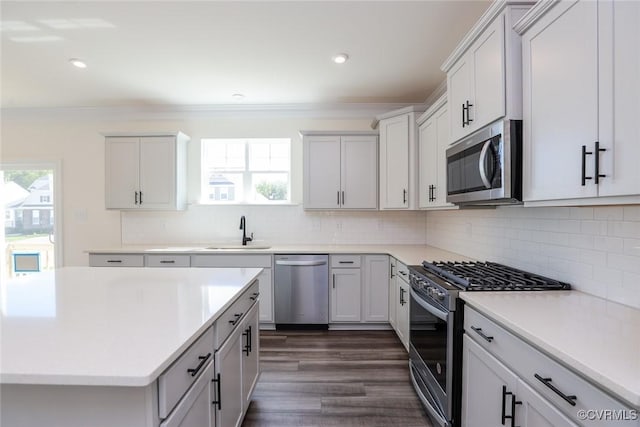 kitchen with a wealth of natural light, crown molding, appliances with stainless steel finishes, and a sink