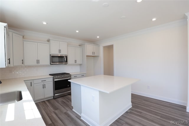 kitchen with decorative backsplash, white cabinetry, hardwood / wood-style flooring, a center island, and stainless steel appliances