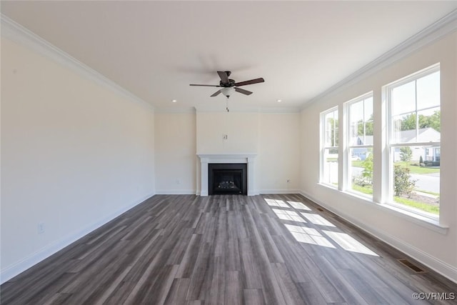 unfurnished living room featuring dark wood-type flooring, a fireplace, a ceiling fan, baseboards, and crown molding