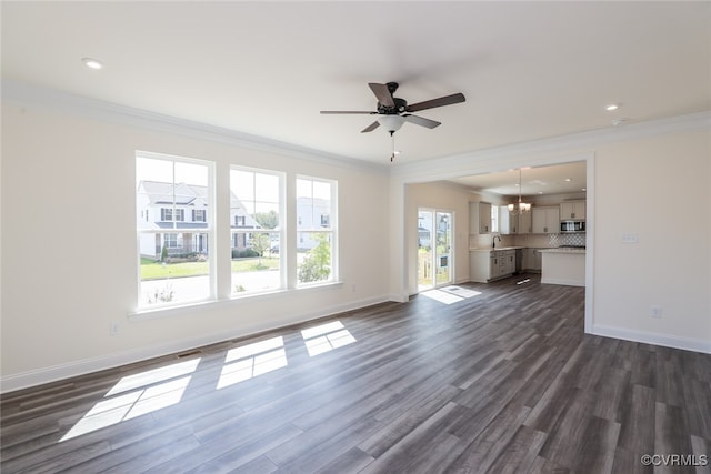 unfurnished living room with sink, ceiling fan with notable chandelier, crown molding, and dark hardwood / wood-style floors