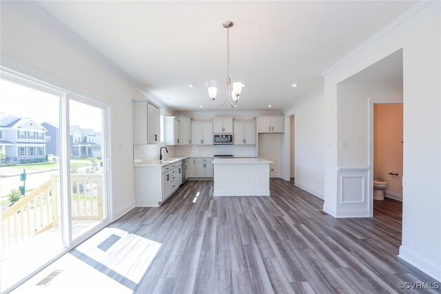 kitchen with a center island, decorative light fixtures, wood-type flooring, decorative backsplash, and white cabinets