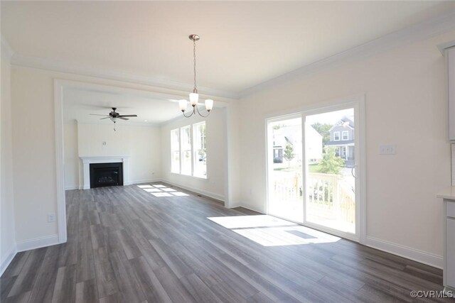 unfurnished living room featuring a wealth of natural light, ceiling fan with notable chandelier, dark hardwood / wood-style floors, and ornamental molding