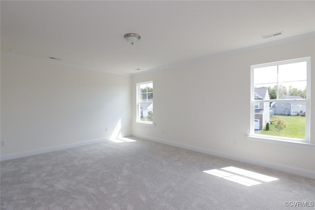 carpeted empty room with ornamental molding, visible vents, and baseboards