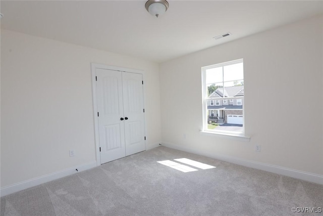 unfurnished bedroom with carpet floors, baseboards, visible vents, and a closet