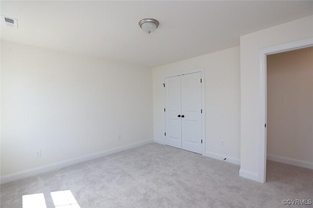 unfurnished bedroom with light colored carpet and a closet