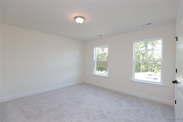 unfurnished room featuring light colored carpet, visible vents, and baseboards