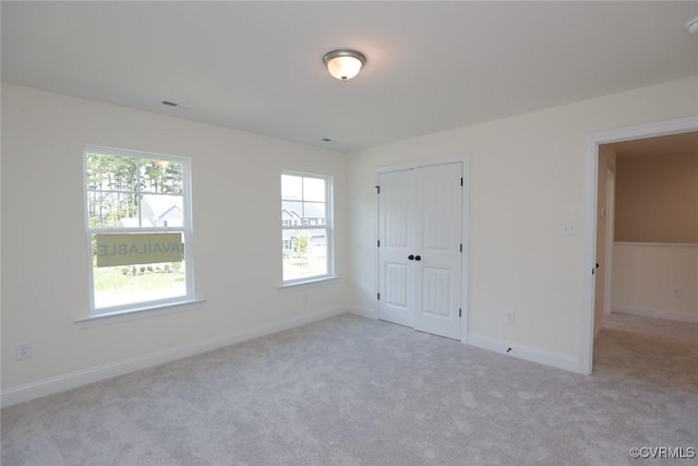 unfurnished bedroom with a closet, carpet flooring, visible vents, and baseboards