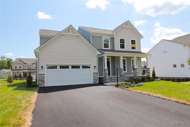 view of front of property with an attached garage, covered porch, stone siding, and a front yard