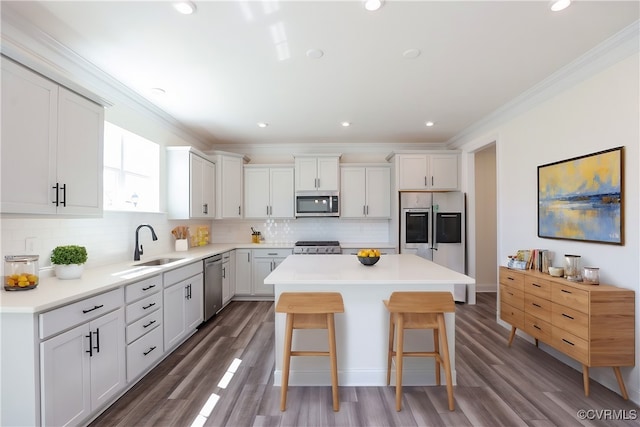 kitchen with appliances with stainless steel finishes, decorative backsplash, sink, wood-type flooring, and a center island