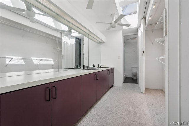 bathroom featuring ceiling fan, vanity with extensive cabinet space, and toilet