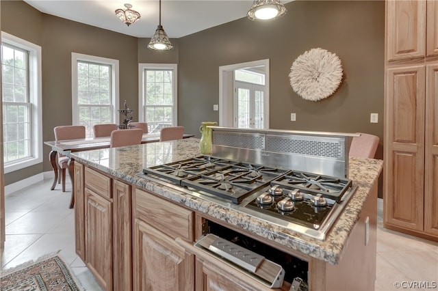 kitchen featuring stainless steel gas cooktop, decorative light fixtures, a center island, and plenty of natural light