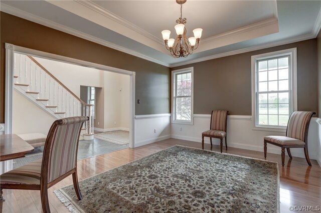 interior space with light hardwood / wood-style floors, crown molding, a chandelier, and a tray ceiling