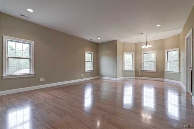 spare room featuring light hardwood / wood-style flooring and a chandelier