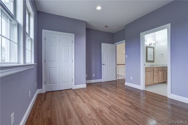 unfurnished bedroom with light hardwood / wood-style floors, a closet, and ensuite bathroom