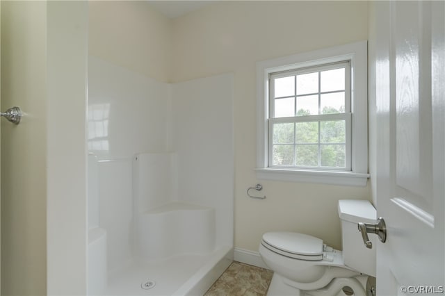 bathroom featuring tile patterned flooring, toilet, and walk in shower