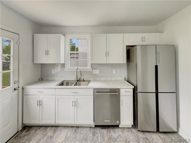 kitchen with appliances with stainless steel finishes, sink, tasteful backsplash, and white cabinets