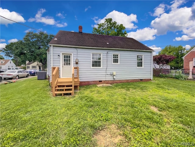 rear view of house with central AC and a yard