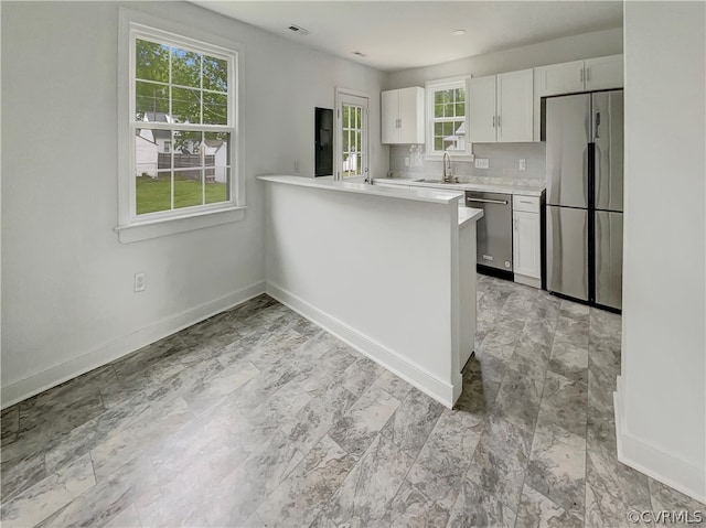 kitchen with plenty of natural light, tasteful backsplash, light tile floors, and stainless steel appliances