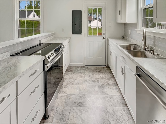 kitchen with appliances with stainless steel finishes, sink, light tile flooring, backsplash, and white cabinetry