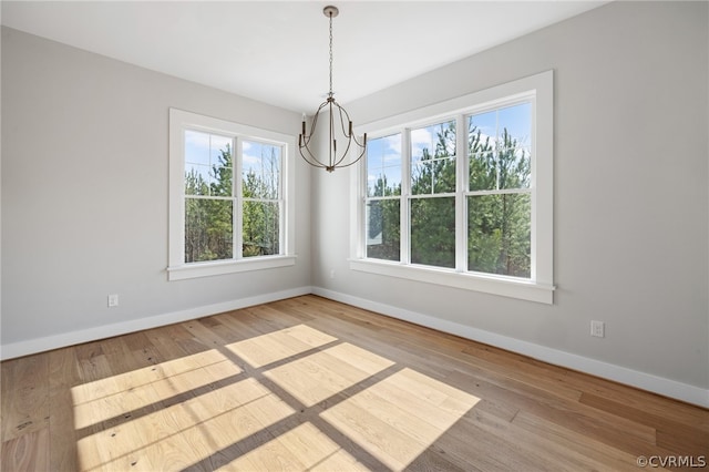 spare room with hardwood / wood-style floors and a chandelier