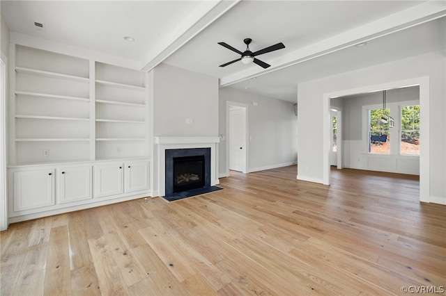 unfurnished living room with built in features, ceiling fan, light hardwood / wood-style flooring, and beamed ceiling