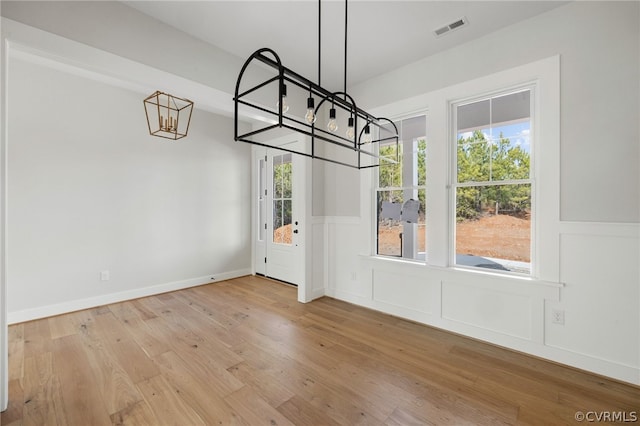 spare room with light hardwood / wood-style floors and an inviting chandelier