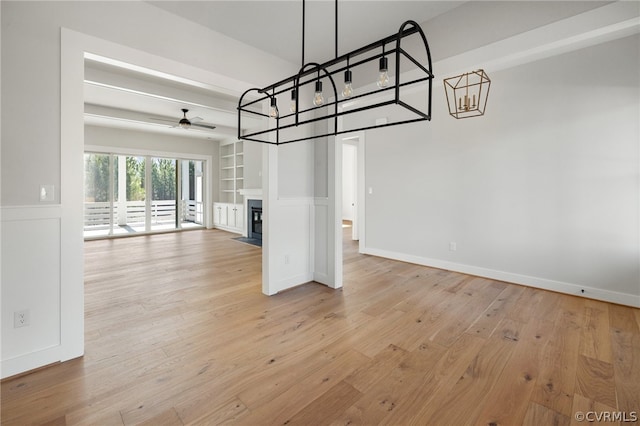 unfurnished living room featuring light wood-type flooring and ceiling fan with notable chandelier