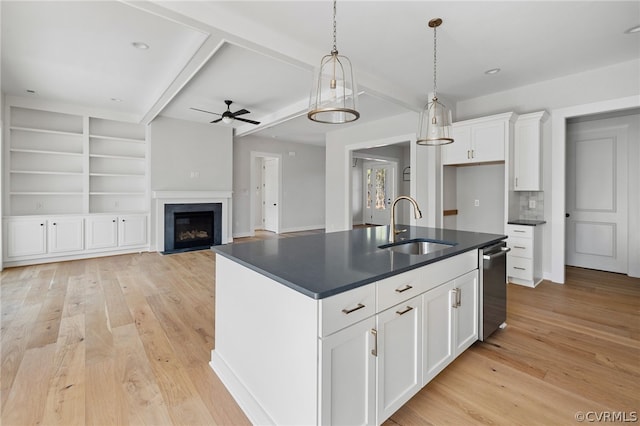 kitchen with ceiling fan, light hardwood / wood-style floors, an island with sink, sink, and white cabinetry