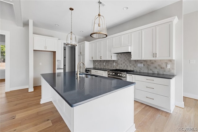 kitchen featuring light hardwood / wood-style flooring, high end stainless steel range oven, sink, tasteful backsplash, and custom exhaust hood