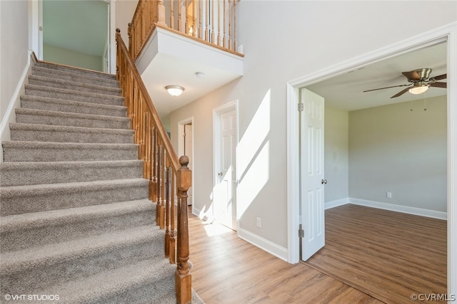 stairs featuring wood-type flooring and ceiling fan