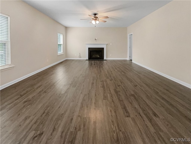 unfurnished living room with a wealth of natural light, ceiling fan, and dark hardwood / wood-style floors